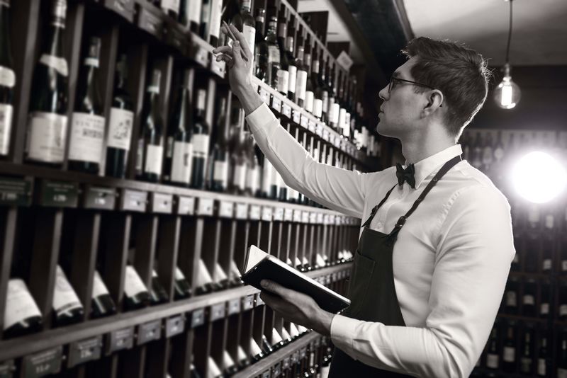 Sommelier writes at notes, putting down information on wine products in cellar